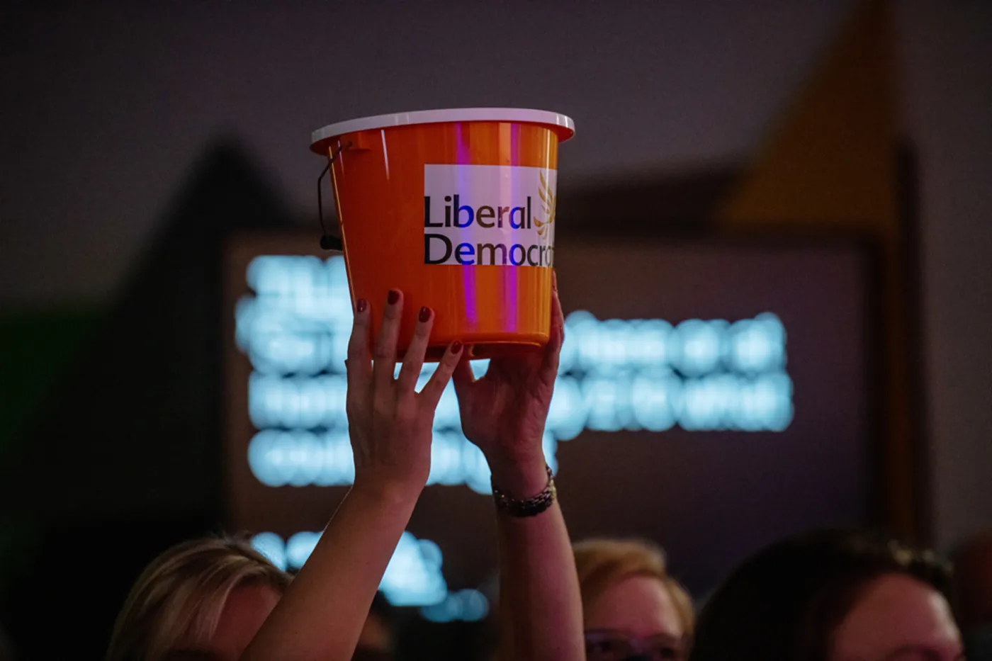 A Liberal Democrat supporter holds up a donation bucket at a party conference in 2021